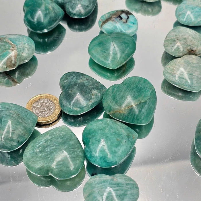 Amazonite Crystal Pocket Hearts displayed with a coin, showcasing their soothing turquoise colors and polished finish.