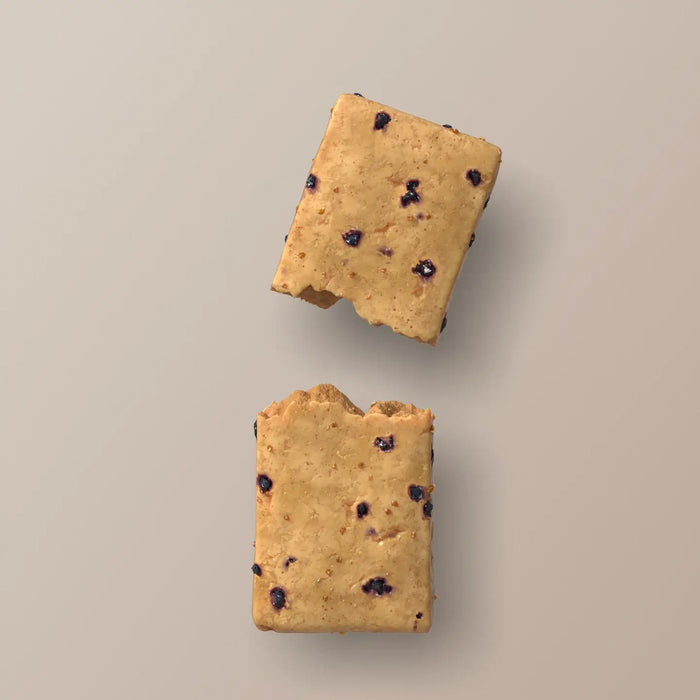 A blue wrapper labeled “STARS+HONEY - MAPLE BLUEBERRY MUFFIN”—a tasty collagen protein bar blending maple and blueberry flavors from the brand STARS+HONEY—rests on a beige surface, with nutritional information visible.