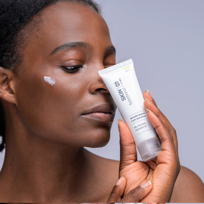 Woman applying skincare product to her face with a focus on the product packaging.