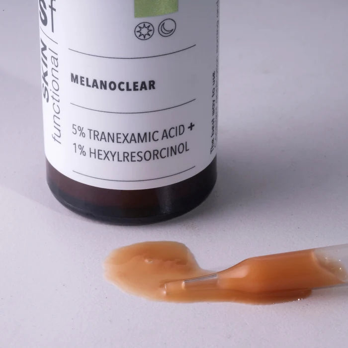 Bottle of Melanoclear with a dropper and brown liquid on a light gray background