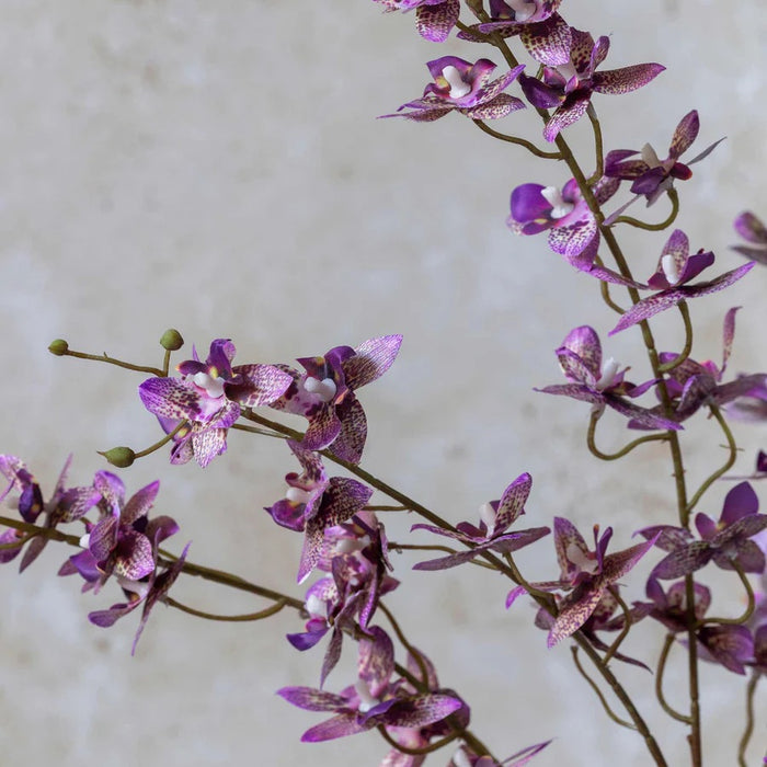 The ABIGAIL AHERN ONCIDIUM ORCHID is a single artificial stem featuring sparse small purple flowers and buds on delicate branches, presented against a plain white background.