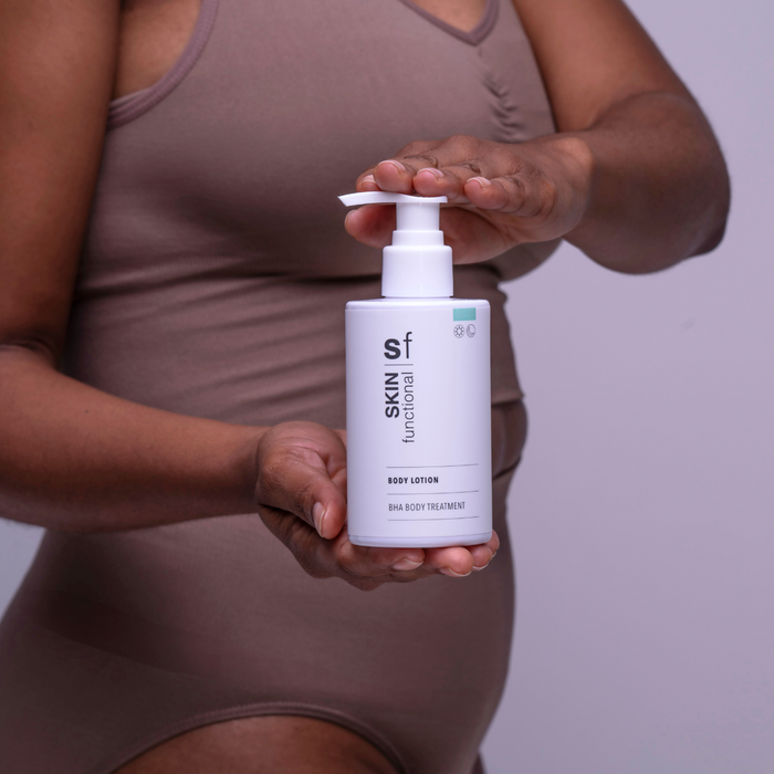 Person holding a bottle of Skin Functional body lotion against a neutral background