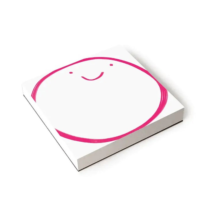 The E. FRANCES – CHUNKY NOTEPAD BIG SMILE by E. FRANCES PAPER features a playful pink smiley face on a white 6x6 notepad with thick chipboard backing.