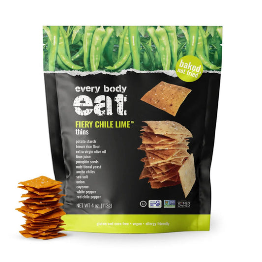 A bag of EVERY BODY EAT FIERY CHILE LIME SNACK THINS 1 OZ is displayed, with allergy-friendly thins from EVERY BODY EAT stacked in front. The packaging promotes these vegan, gluten-free snacks as allergy-friendly and features an image of green beans at the top.