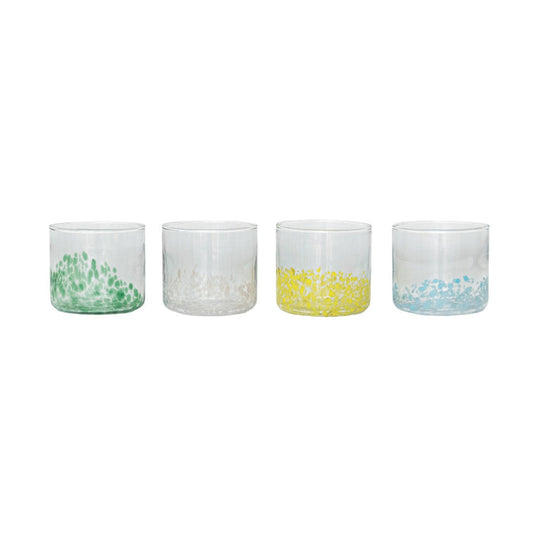 A round tray displays two CREATIVE COOP HAND-BLOWN ROUND CONFETTI DRINKING GLASSES with beverages, decorative stirrers, a green bottle, lemonade bottle, and a small cactus ornament on a tabletop with light linens.