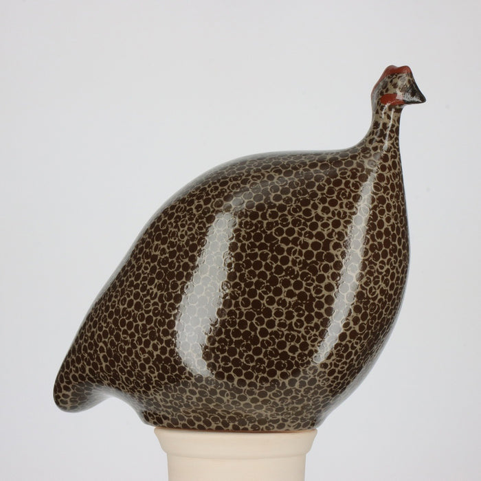 The LES CERAMIQUES DE LUSSAN - PETITE CERAMIC FRENCH GUINEA IN BLACK SPOTTED GREY captures the essence of French brood guinea fowl with its glossy, speckled black and grey finish atop a light base. Its rounded, streamlined design embodies the minimalist yet realistic charm characteristic of LES CERAMIQUES DE LUSSAN's handmade creations.