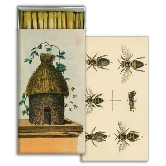 The HOMART MATCHES - HIVE & 6 BEES is a vintage-style match box with a straw beehive and bee illustration, partially open to show safety matches and a bee diagram inside. Measures 4.5 x 2.25 inches—great for collectors or as a hostess gift.