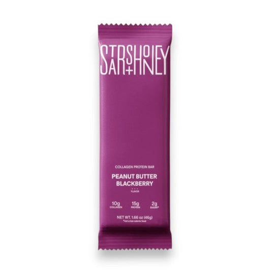 A purple STARS+HONEY - PEANUT BUTTER BLACKBERRY protein bar rests on a beige surface, with its wrapper highlighting 10g collagen, 15g protein, and 2g sugar.