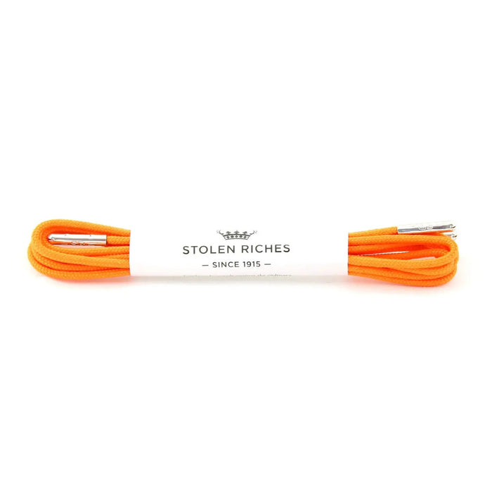 A pair of brown leather brogue shoes with decorative perforations features STOLEN RICHES - DRESS SHOELACE IN TIQUI ORANGE by STOLEN RICHES, shown on a white background.