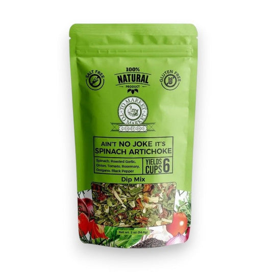 A green bag of TO MARKET - SPINACH ARTICHOKE DIP MIX from TO MARKET- DIPS & SPREADS stands behind a white bowl filled with spinach artichoke dip and crackers. Made with roasted garlic and natural ingredients, this gluten free mix makes six cups.