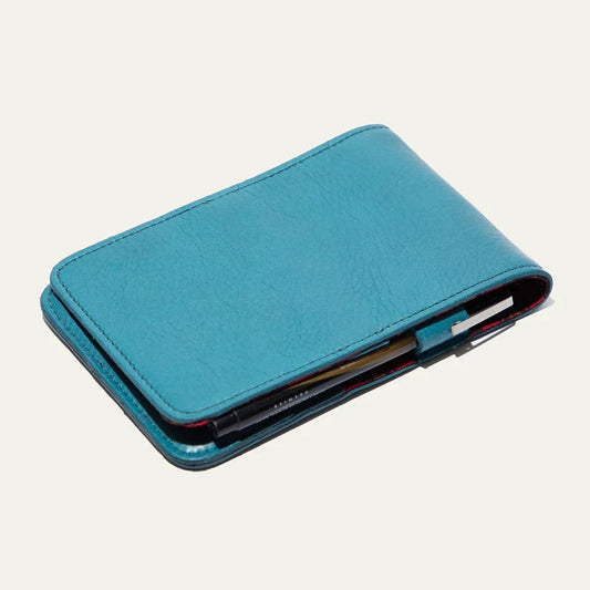 The WILL LEATHER GOODS - GOLF YARDAGE BOOK IN TURQUOISE is a full-grain leather cover, partially open to display notebook pages and cards—ideal for organizing your golf scorecard or yardage book.