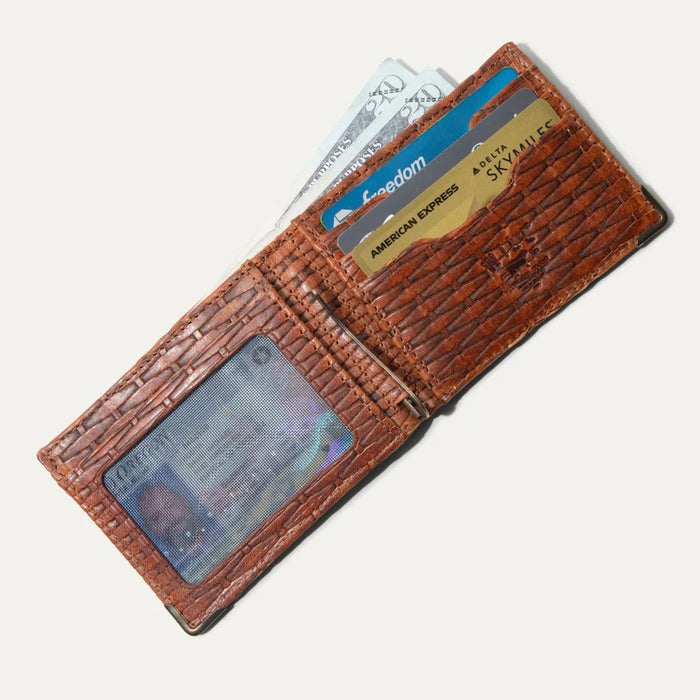 The WILL LEATHER GOODS - THE INDUSTRIALIST BILLFOLD IN COGNAC BASKETWEAVE, made from full-grain leather with a woven texture, shows an empty ID slot with a black mesh window on the left. The wallet rests open on a light surface.