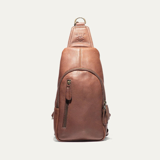 The WILL LEATHER GOODS - Zip Around Sling Bag in Cognac, featuring full-grain leather, a front zipper pocket, adjustable strap, and top handle, is shown upright against a plain light background.